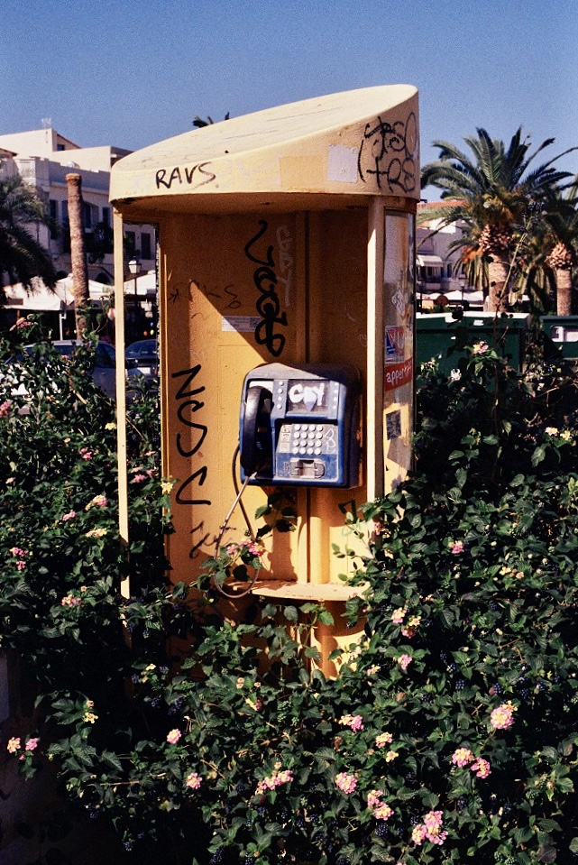 analog photograph of a yellow public payphone